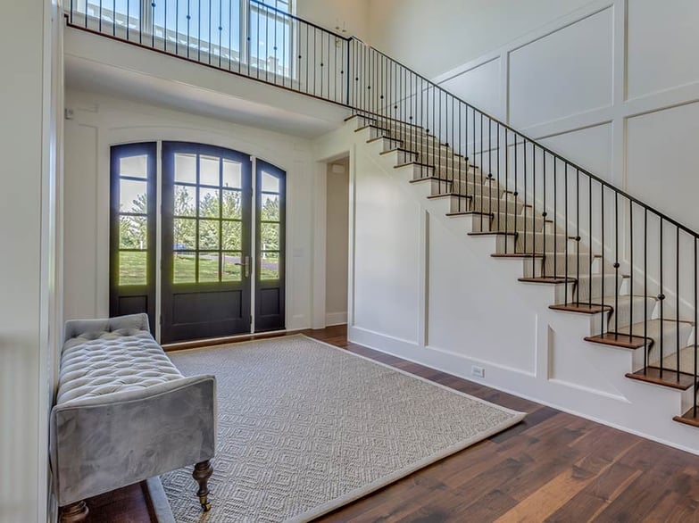 House foyer with wood door, wood floors, and stairs.