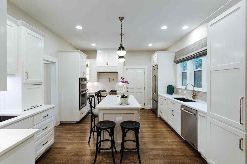 Contemporary white kitchen with an island and pendant lighting, designed by J. Bryant Boyd in Central Texas Hill Country