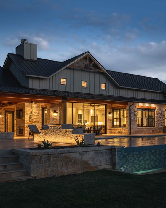 House exterior with a lit patio and pool at night in central Texas | J Bryant Boyd