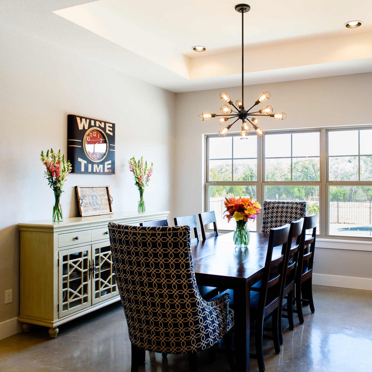 Modern dining room with a unique chandelier and large windows, part of a remodel by J. Bryant Boyd in Georgetown, TX