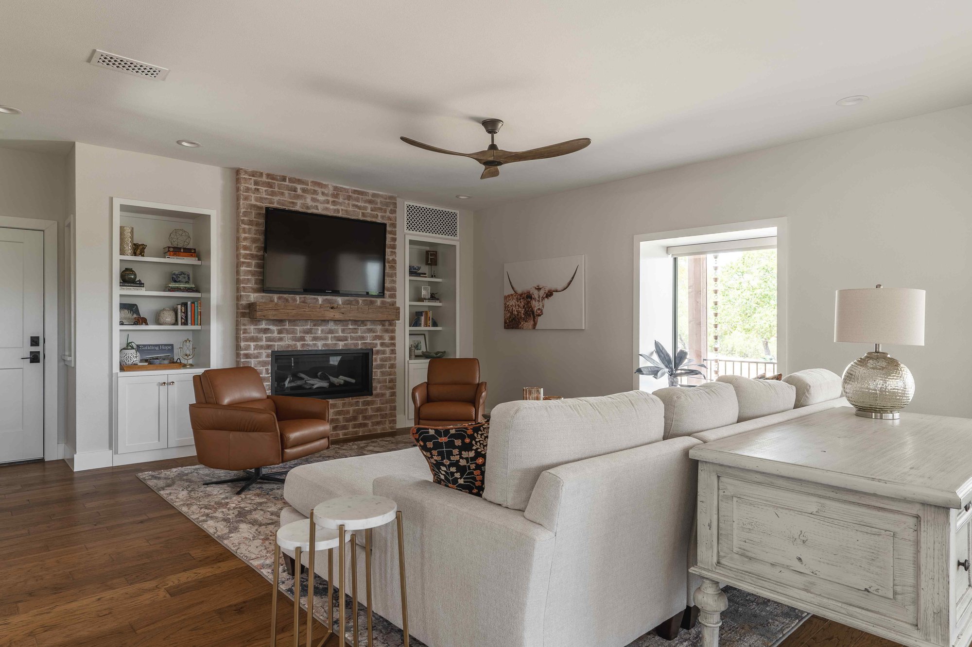 Living room with brick back wall housing a TV and modern couch | J Bryant Boyd