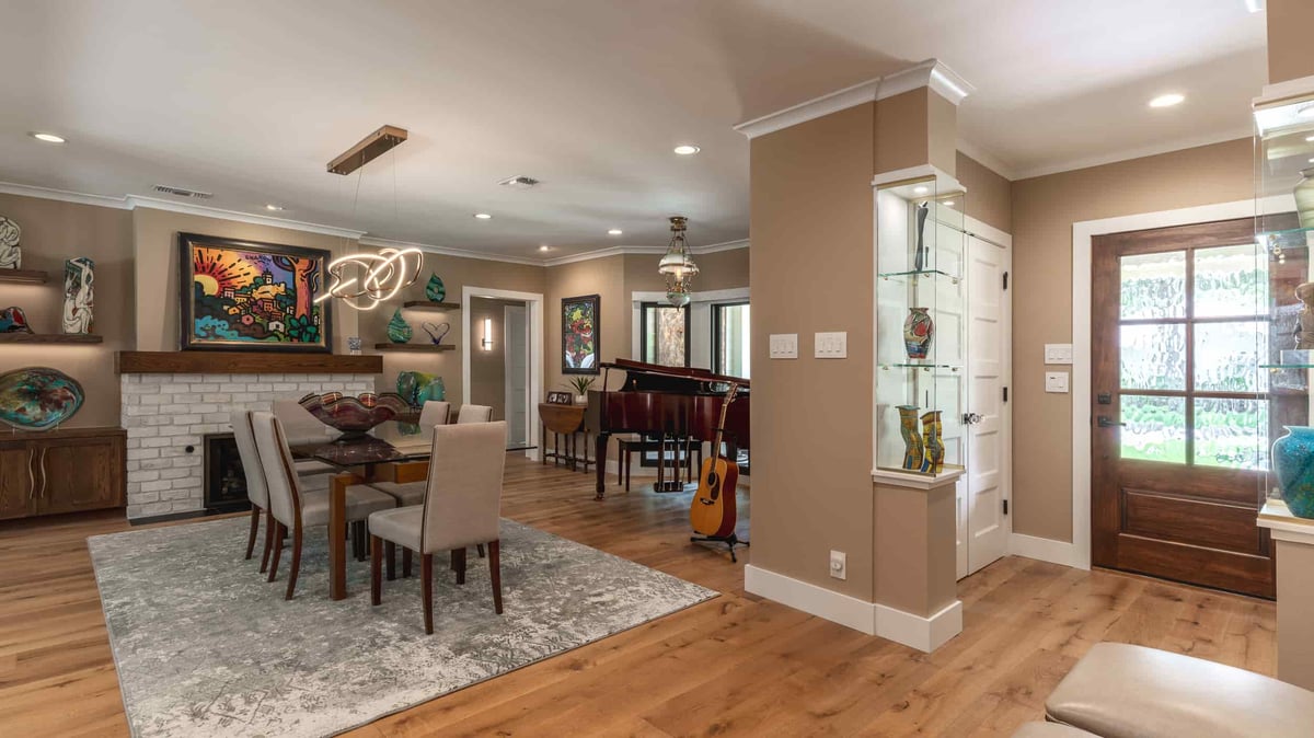 A stylish Texas living room designed by J Bryant Boyd, highlighting a piano and a fireplace, perfect for relaxation and music.