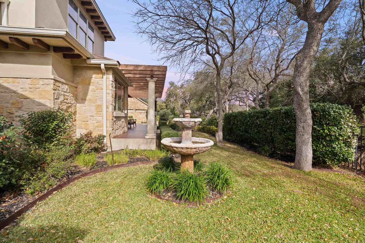 Backyard garden with stone water fountain in a custom home by J Bryant Boyd, Georgetown TX