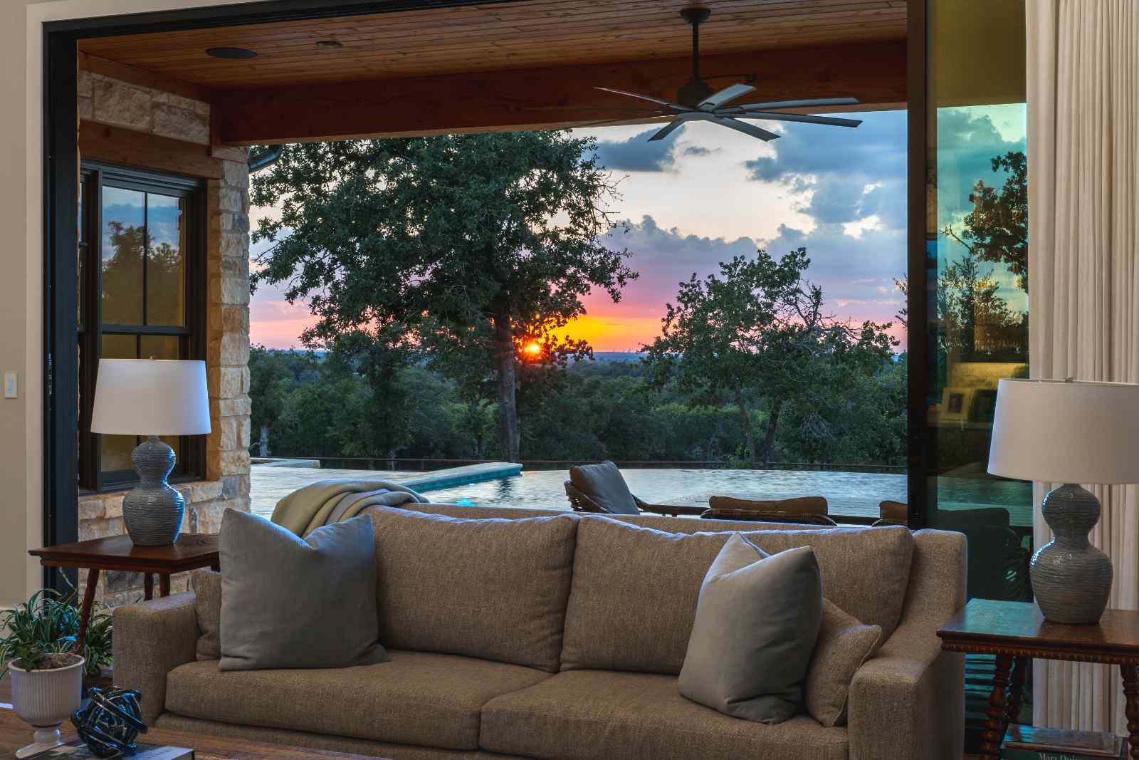 Living room view overlooking the pool and sunset in a custom home by J. Bryant Boyd in Central Texas