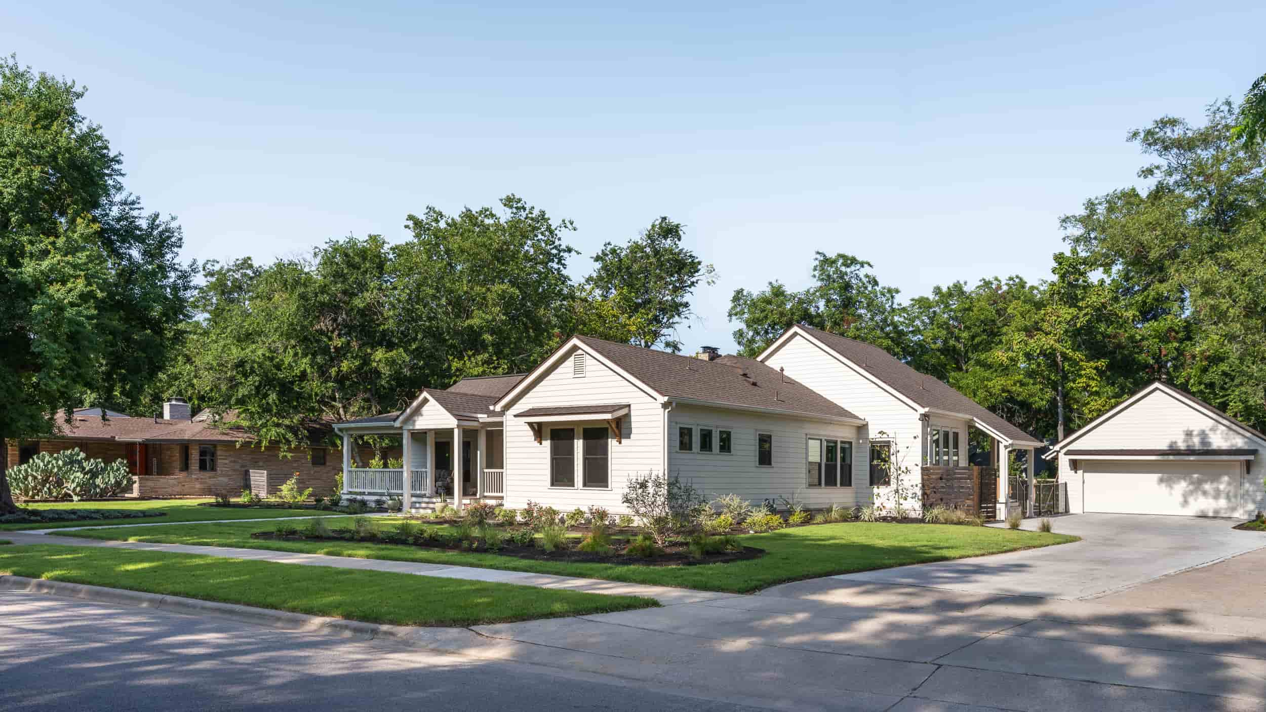  A Texas home featuring a driveway and trees in the front yard, captured by J Bryant Boyd.