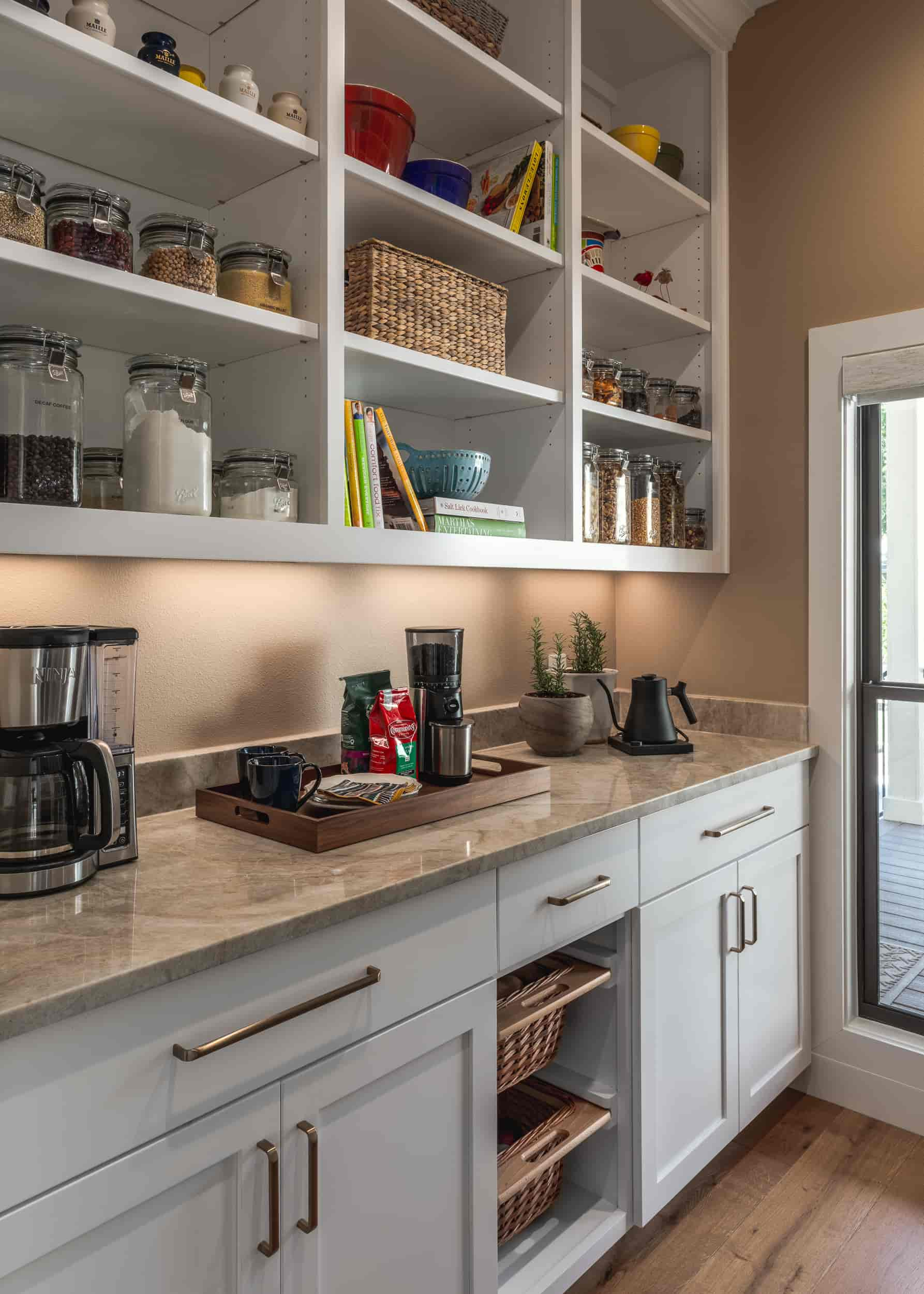 A bright kitchen featuring white cabinets and a window, designed by J Bryant Boyd, located in Texas.