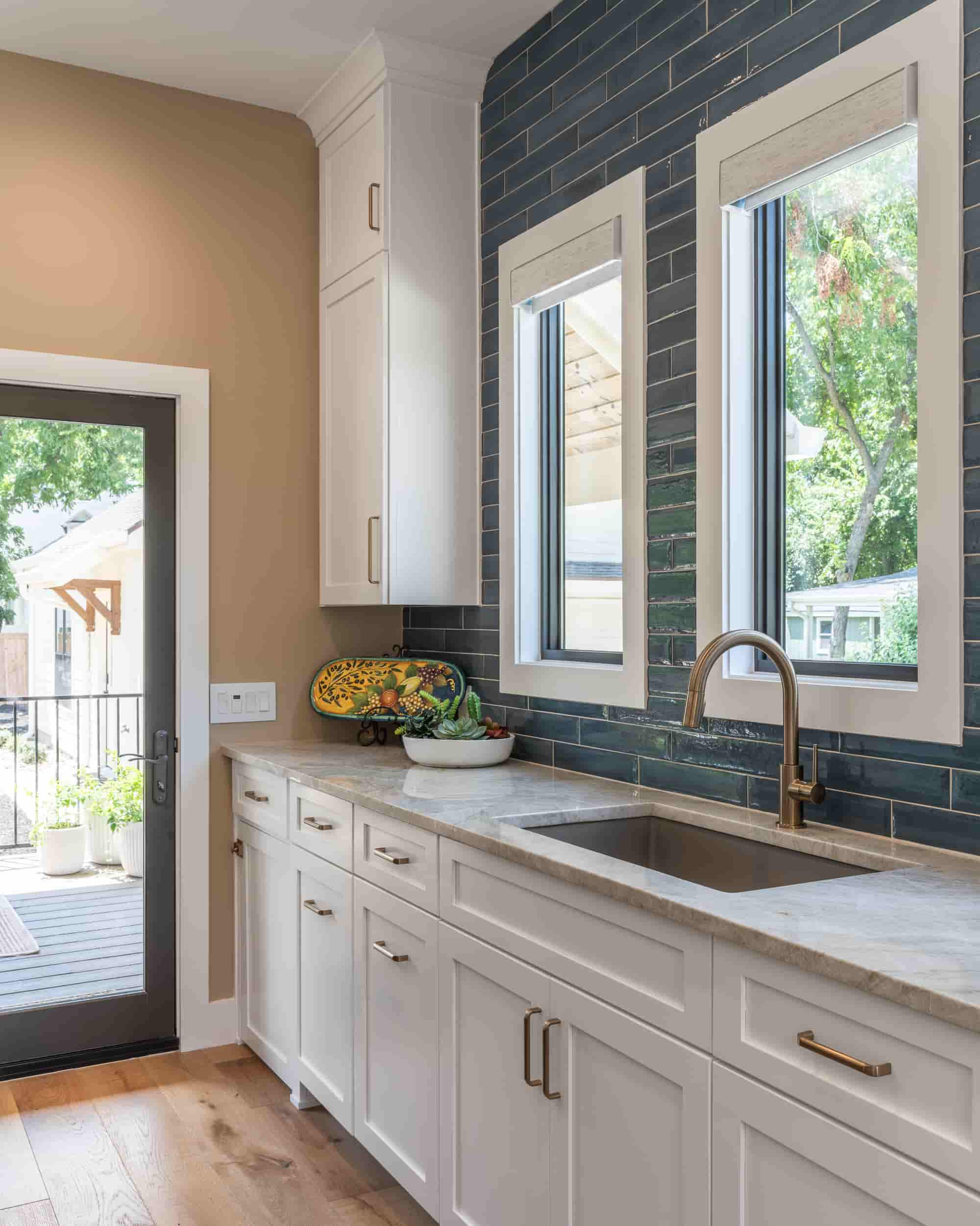 A contemporary kitchen in Texas, showcasing white cabinets and blue tile, designed by J Bryant Boyd.